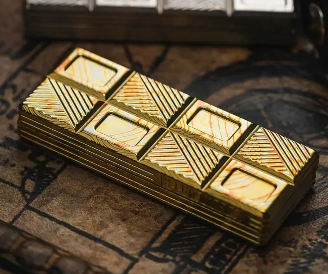 A gold 01EDC Wafer 2.0 slider, chocolate-bar segments catching the light, on a dark map